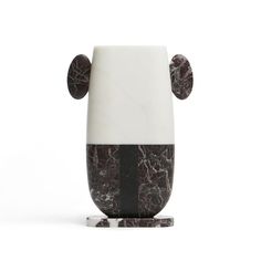 a black and white vase sitting on top of a marble base with two circles around it