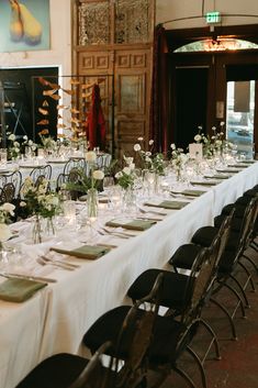 a long table is set up with white flowers and greenery for an elegant dinner