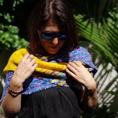 a woman wearing sunglasses and a knitted shawl in front of some palm trees