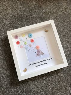 a white frame with buttons in it sitting on the floor next to a stuffed animal