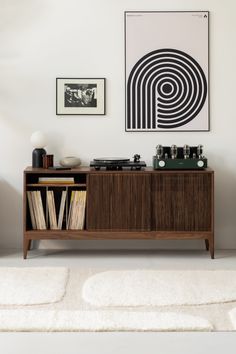 a record player sitting on top of a wooden cabinet next to a wall with pictures above it