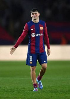 a soccer player is on the field with his hand out and smiling at the camera