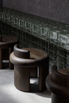 three wooden stools sitting next to each other in front of a brick wall and floor