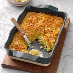 a casserole dish on a wooden cutting board with a serving utensil