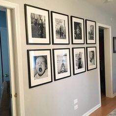 a wall that has pictures on it with black and white photos hanging up against the wall