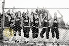 a group of young women standing next to each other behind a chain link fence with their arms in the air