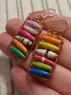 a person is holding some colorful crayons in their hand and they are wearing earrings