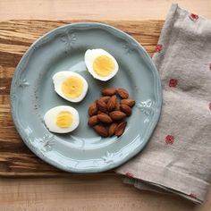 three hard boiled eggs and almonds on a blue plate next to a gray napkin