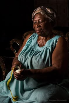 an older woman sitting in a chair holding a banana