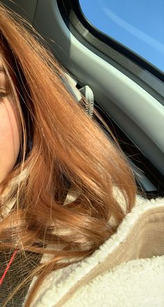 a woman with long red hair sitting in the back seat of a car talking on her cell phone