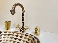 a bathroom sink with two faucets and a gold cup on the counter top