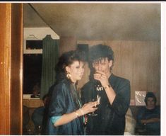 a man and woman standing next to each other holding wine glasses in front of them