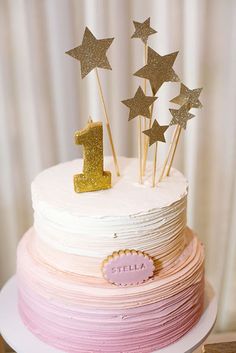 a pink and white cake with gold stars on top