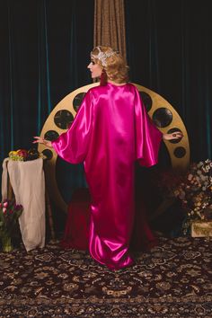 a woman in a pink dress standing next to a clock