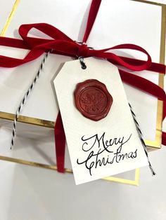 a red wax stamp sitting on top of a white box next to a red ribbon