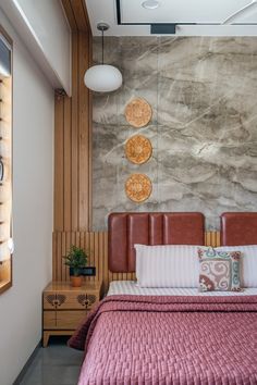 a bed with pink bedspread and pillows in a bedroom