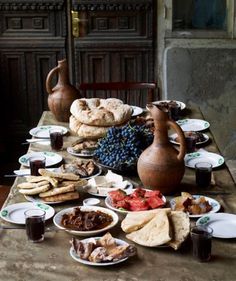 a table filled with food and drinks on top of a wooden tablecloth covered in plates