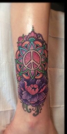 a woman's foot with a flower and peace sign tattoo on the side of her leg