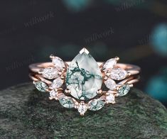 a close up view of a ring with green and white stones in it on top of a rock