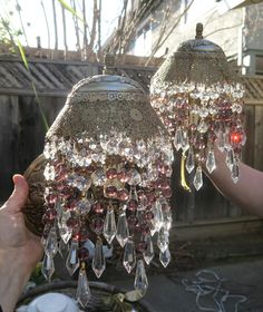 two chandeliers are being held by someone's hands in front of a fence