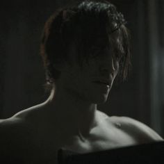 a shirtless man in the dark looking at something