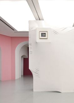 a room with pink walls and white furniture on the floor in front of an arch