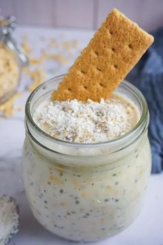 a cracker sticking out of the top of a jar filled with cheesecake dip