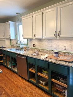 a kitchen with white cabinets and green island in the center is being worked on by an expert