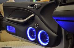 the inside of a car with blue lights on it's dash light and door handle