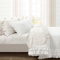 a bed with white sheets and pillows on top of it in front of a window