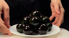 a person is placing green peppers on a white plate