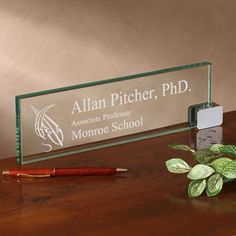 a glass award sitting on top of a wooden desk next to a pen and pencil