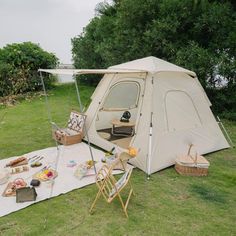 a tent set up in the grass with picnic items on it and an open door