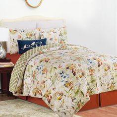 a bed with a floral comforter and pillows