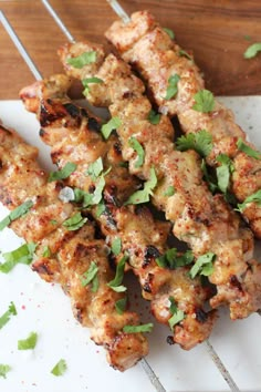 chicken skewers with cilantro and parsley sitting on a white plate