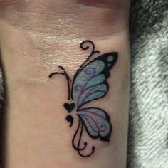 a small butterfly tattoo on the wrist with hearts and swirls around it's wings