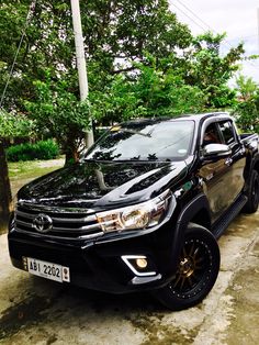 a black truck parked in front of some trees