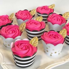 cupcakes decorated with pink frosting and gold leaf decorations on a white plate