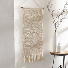 the wall hanging is decorated with white and beige accents, along with a plant in a vase