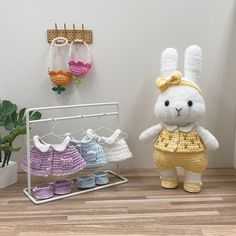 a stuffed rabbit is standing next to some crocheted clothes