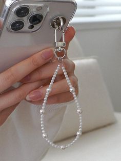 a person holding a cell phone with a chain attached to the back of their phone