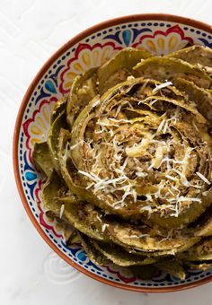 artichokes with shredded cheese in a colorful bowl on a white tablecloth