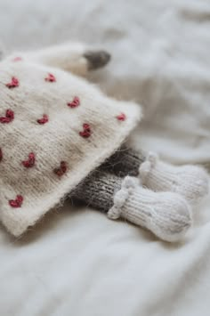 a cat laying on top of a bed next to a white blanket with red hearts