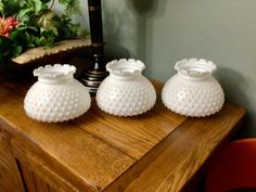 three white vases sitting on top of a wooden table