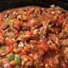 a close up of a stew in a pot with meat and beans on the side