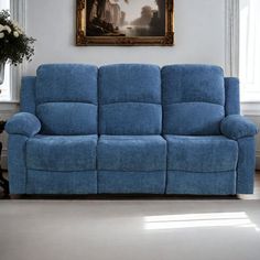 a blue reclining couch in a living room next to a painting on the wall