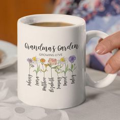 a woman holding a coffee mug with the names of grandmas garden growing love on it