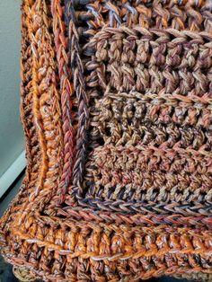 an orange and brown crocheted blanket sitting on top of a table