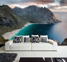 a couch sitting in front of a large wall mural with mountains and the ocean behind it