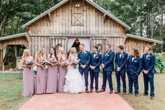 a bride and groom with their bridal party in front of a barn at the farm